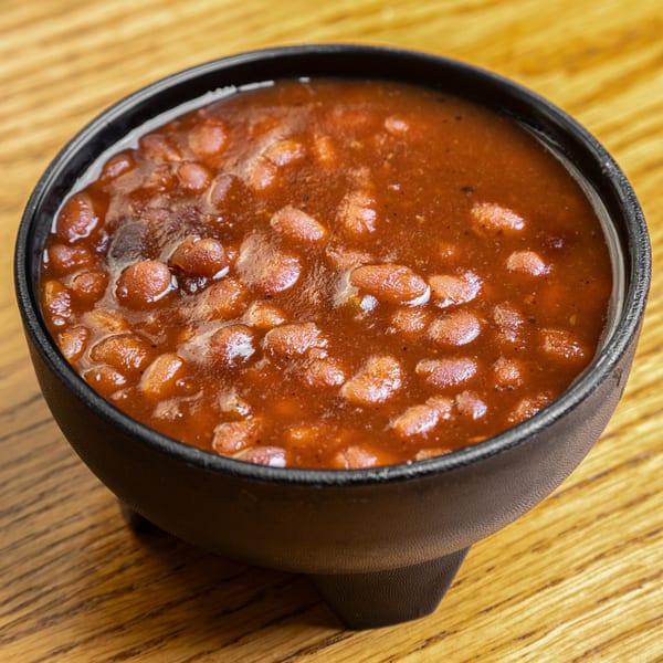 A black bowl filled with Hump's BBQ baked beans in a rich, reddish-brown sauce.