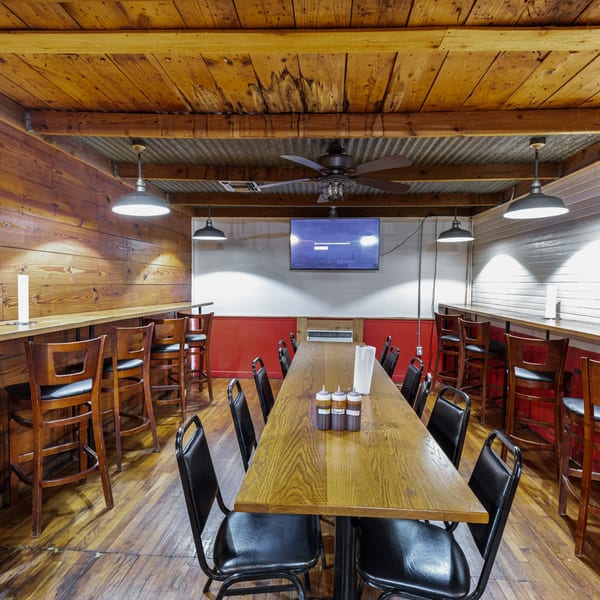Hump's BBQ dining room with long wooden tables, bar seating, and a TV on the wall.