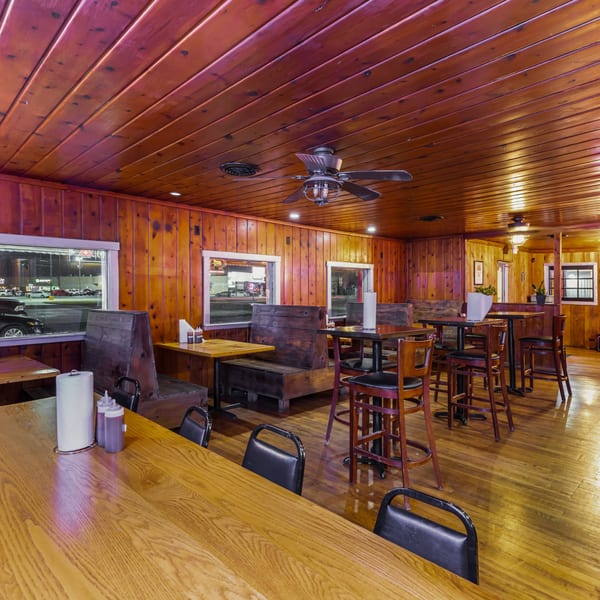 Interior of Hump's BBQ, featuring wooden walls and ceiling, booths, high-top tables, and bar stools.
