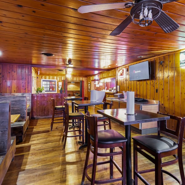 Interior of Hump's BBQ, featuring wooden walls, floors, and ceiling, with high-top tables and booths.