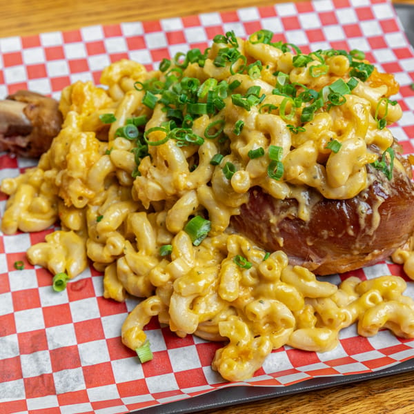 Hump's BBQ mac and cheese piled high on a baked potato, garnished with green onions.