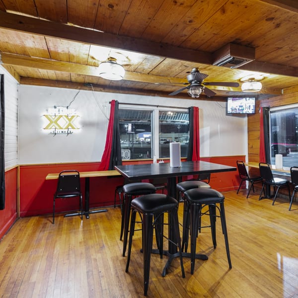 Hump's BBQ interior with wooden floors and ceiling, red walls, black tables, and a neon sign.