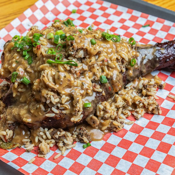 Hump's BBQ's smothered turkey leg, topped with dirty rice, gravy, and green onions.