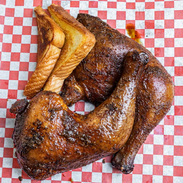 Hump's BBQ chicken, glazed and seasoned, with two slices of toasted bread on checkered paper.